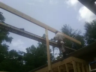 Carpenter setting a ridge beam over a new addition frame — Ice Dam Removal by Roofing Brothers in Wilkinson