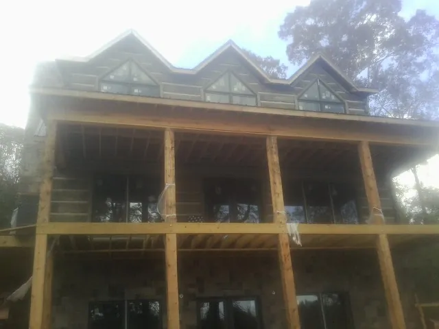 Dormers and porch framing on a large log home under construction — Roof Coating work by our crew in Wilkinson
