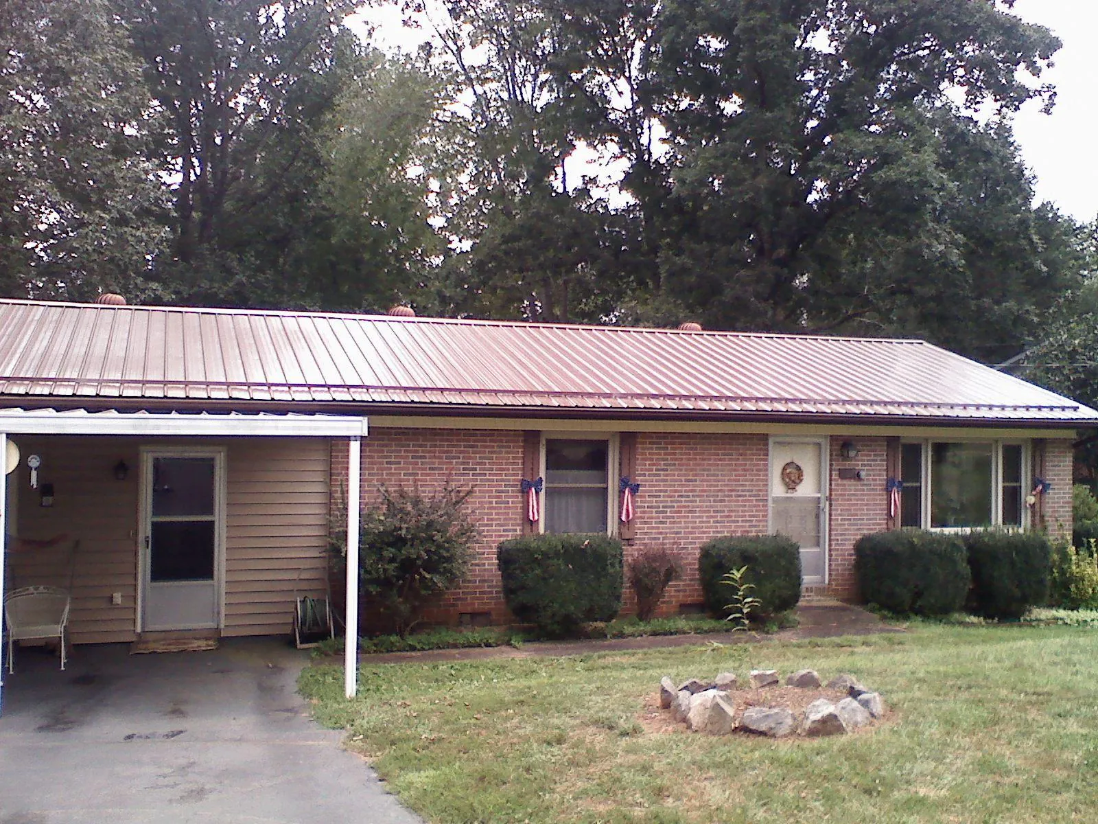 Bronze metal roof and carport on a brick ranch home — Roof Repair work by our crew in Wilkinson